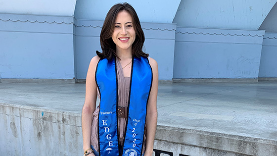 Diana Sanchez standing and smiling wearing a Travelers EDGE graduation sash.