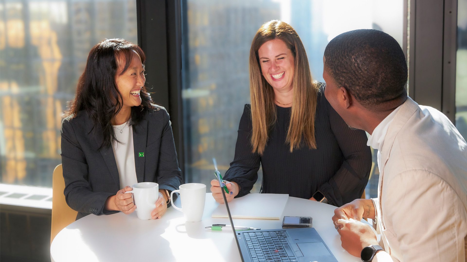 Three TD colleagues share a laugh while working together at a table.